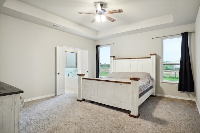 bedroom with light carpet, a raised ceiling, and multiple windows