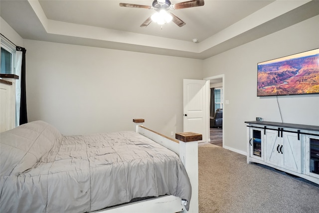 bedroom with carpet, ceiling fan, and a raised ceiling