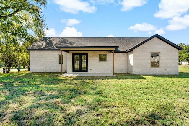 rear view of house with french doors, a lawn, and a patio