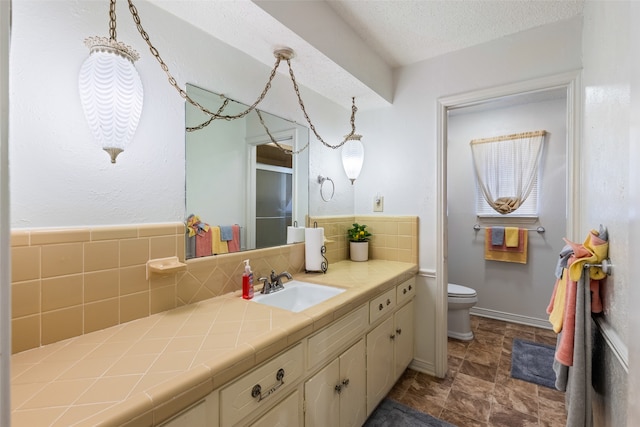 bathroom featuring vanity, toilet, a textured ceiling, and decorative backsplash