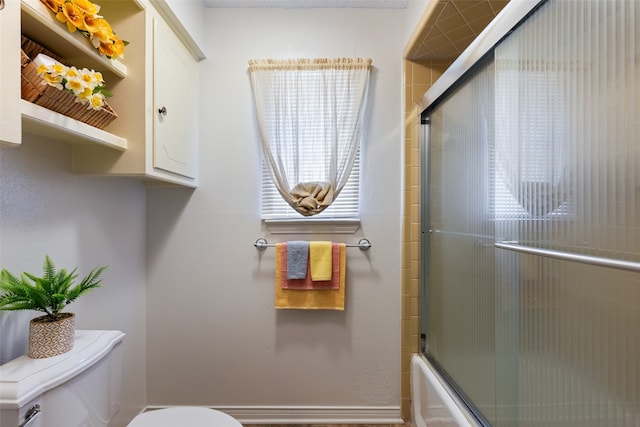 bathroom with combined bath / shower with glass door and toilet