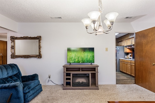 carpeted living room with a textured ceiling and a chandelier