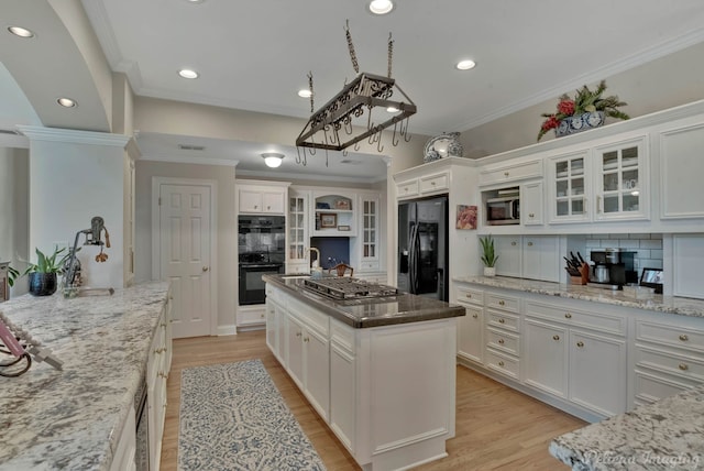 kitchen featuring white cabinets, black appliances, crown molding, a center island, and light hardwood / wood-style flooring