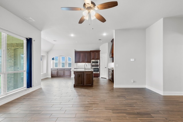 kitchen featuring ceiling fan, sink, a kitchen island with sink, appliances with stainless steel finishes, and hardwood / wood-style floors