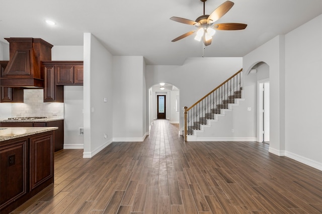 interior space with ceiling fan, backsplash, stainless steel gas stovetop, custom range hood, and dark hardwood / wood-style flooring