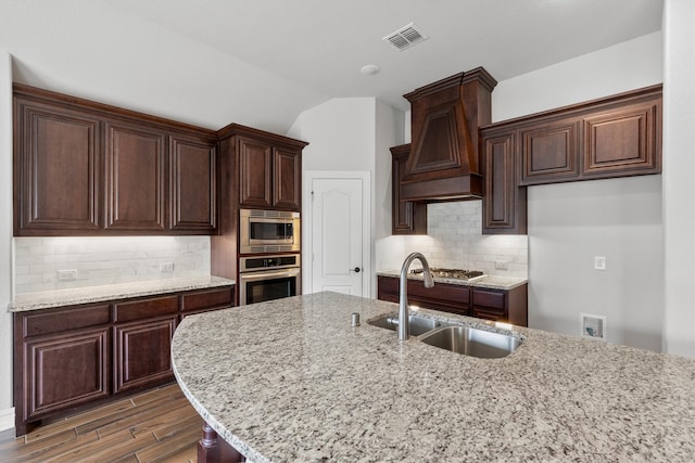 kitchen with sink, vaulted ceiling, stainless steel appliances, backsplash, and dark hardwood / wood-style flooring