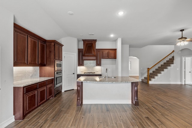 kitchen featuring ceiling fan, a kitchen island with sink, stainless steel appliances, and dark hardwood / wood-style floors