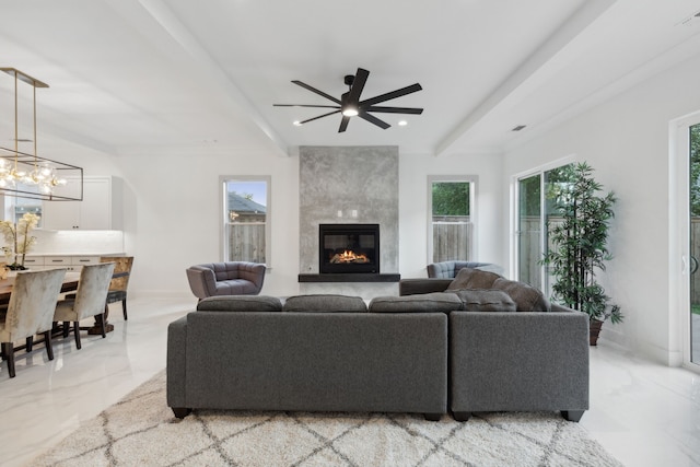 living room featuring ceiling fan with notable chandelier and a large fireplace