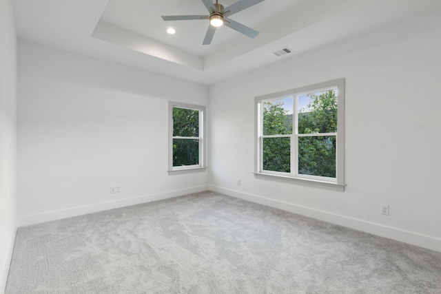 unfurnished room with a tray ceiling, ceiling fan, and light colored carpet