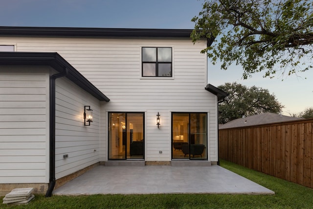 back house at dusk featuring a patio area