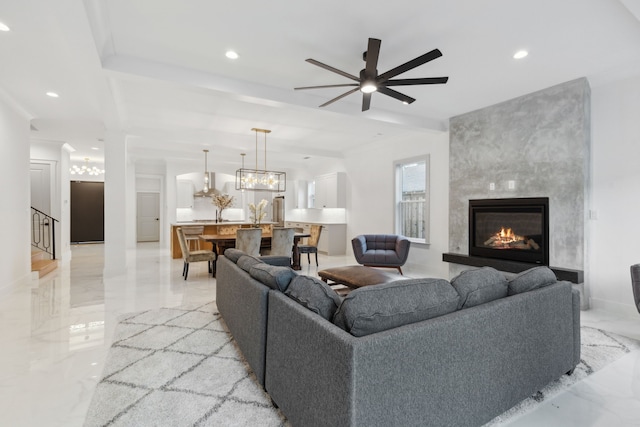 living room featuring ceiling fan with notable chandelier and a large fireplace