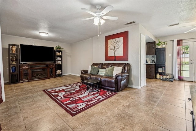 living room with a textured ceiling, ceiling fan, and french doors