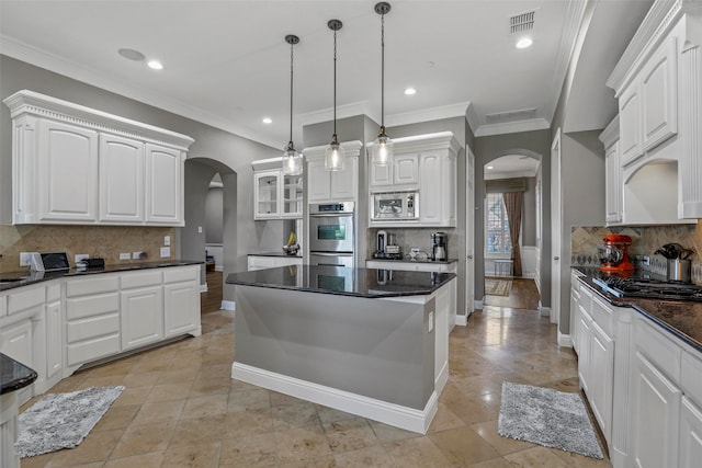 kitchen with white cabinets, decorative backsplash, stainless steel appliances, and decorative light fixtures