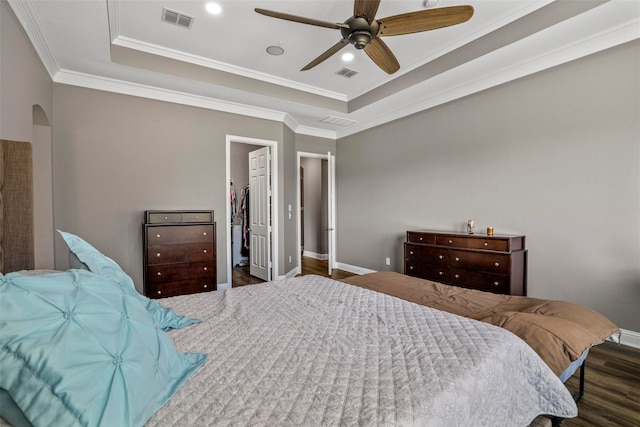 bedroom featuring ceiling fan, dark hardwood / wood-style floors, a raised ceiling, and a spacious closet