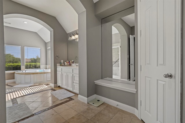 bathroom with a tub, tile patterned floors, a chandelier, lofted ceiling, and vanity