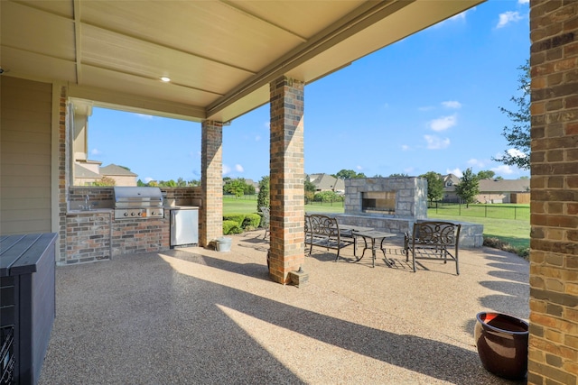 view of patio featuring an outdoor stone fireplace, area for grilling, and grilling area