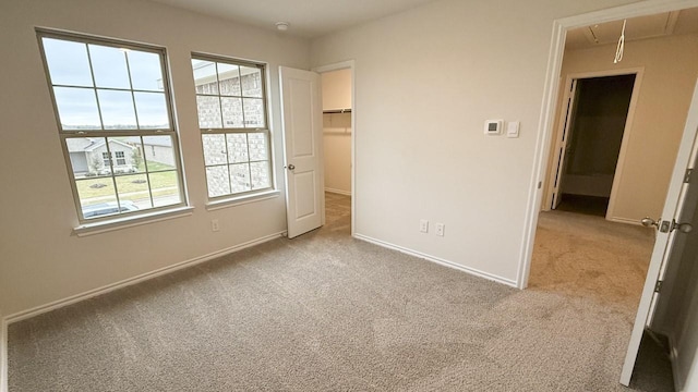 unfurnished bedroom with a walk in closet, light colored carpet, and a closet