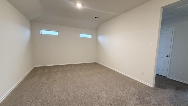 carpeted empty room featuring vaulted ceiling