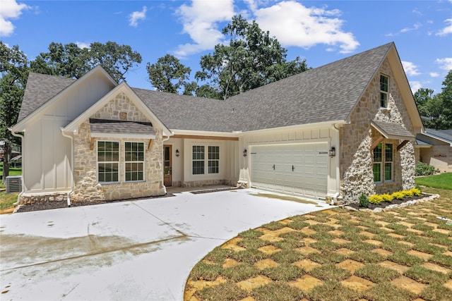 view of front of house featuring cooling unit, a garage, and a front lawn