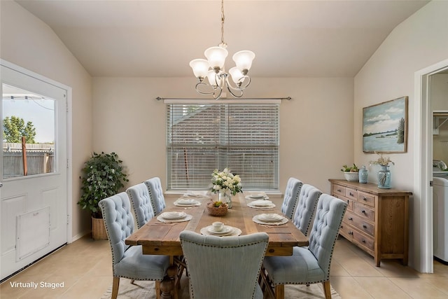 dining room with a notable chandelier, light tile patterned floors, vaulted ceiling, and washer / clothes dryer