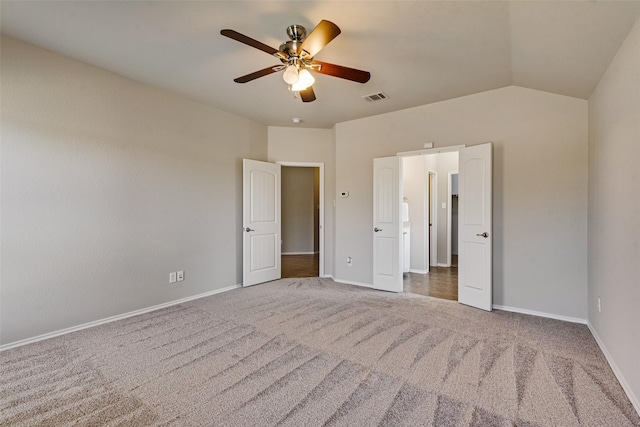 unfurnished bedroom featuring ceiling fan, vaulted ceiling, and dark colored carpet