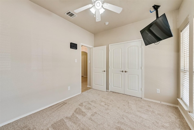 unfurnished bedroom featuring light colored carpet, ceiling fan, and a closet