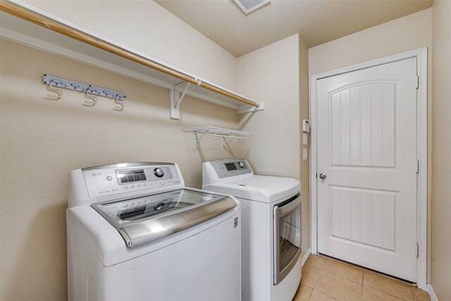 washroom with washer and clothes dryer and light tile patterned floors