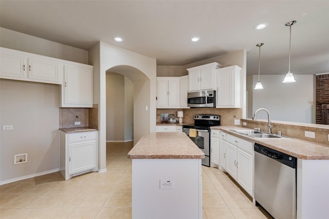 kitchen with sink, decorative light fixtures, kitchen peninsula, stainless steel appliances, and white cabinets