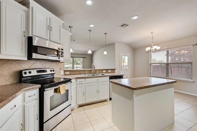 kitchen with pendant lighting, sink, white cabinetry, stainless steel appliances, and a kitchen island