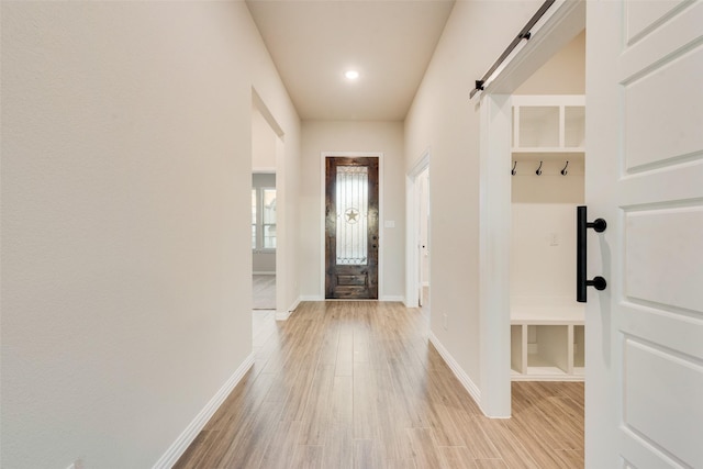 mudroom with a barn door and light wood-type flooring