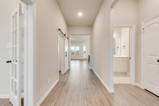 corridor featuring a barn door and light hardwood / wood-style flooring