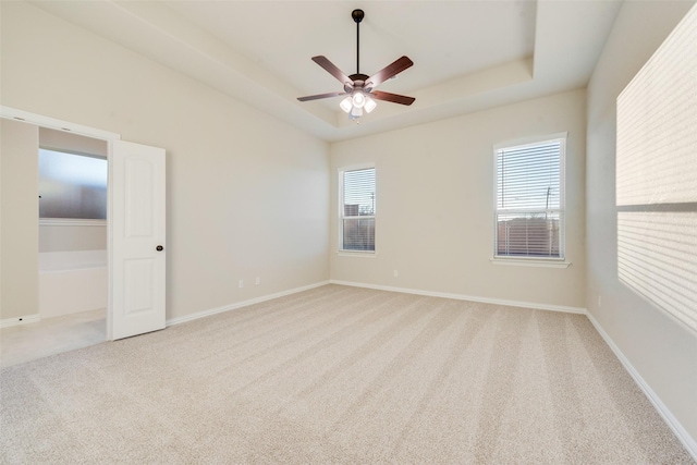 spare room featuring a raised ceiling, ceiling fan, and light colored carpet