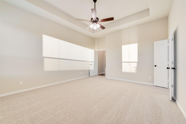 carpeted empty room with a tray ceiling and ceiling fan