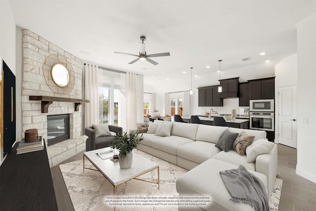 living room featuring ceiling fan, sink, dark wood-type flooring, lofted ceiling, and a fireplace