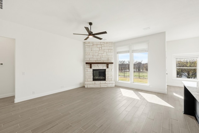 unfurnished living room with ceiling fan, a fireplace, and light wood-type flooring