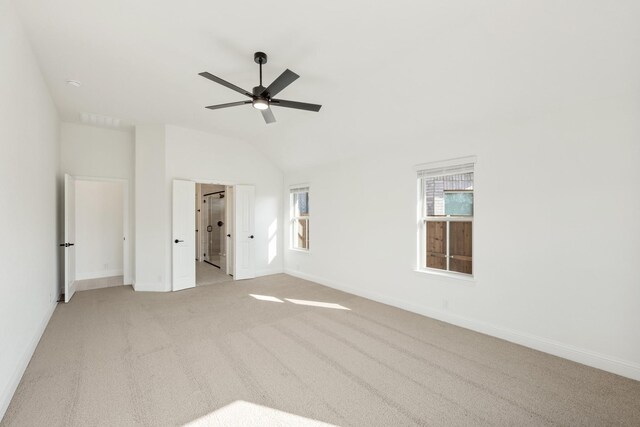 unfurnished bedroom with light colored carpet, vaulted ceiling, and ceiling fan