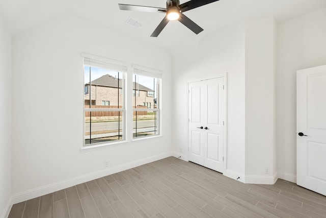 unfurnished bedroom featuring ceiling fan, a closet, light hardwood / wood-style floors, and lofted ceiling