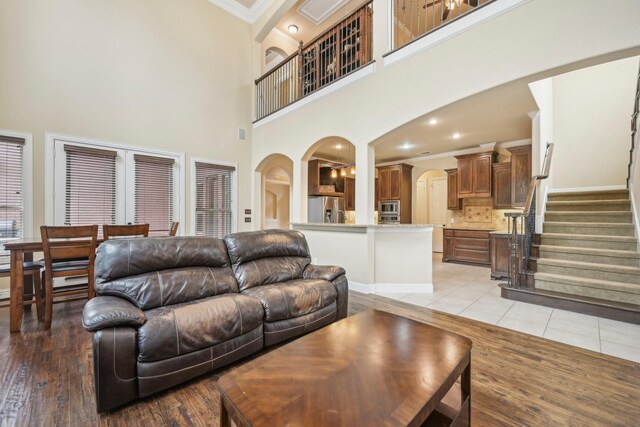 living room featuring light wood-type flooring, crown molding, a high ceiling, and built in shelves