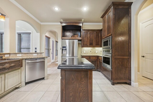 kitchen featuring dark brown cabinets, a center island, appliances with stainless steel finishes, light tile patterned floors, and crown molding