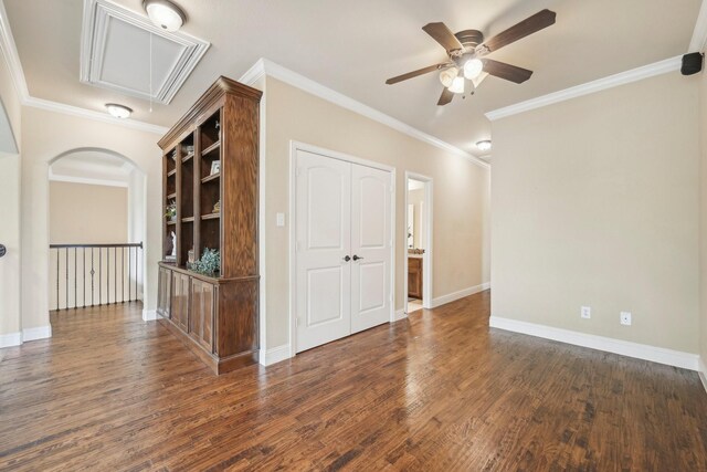 empty room with crown molding, dark wood-type flooring, and ceiling fan