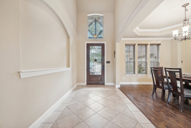 foyer featuring an inviting chandelier, crown molding, and light hardwood / wood-style floors