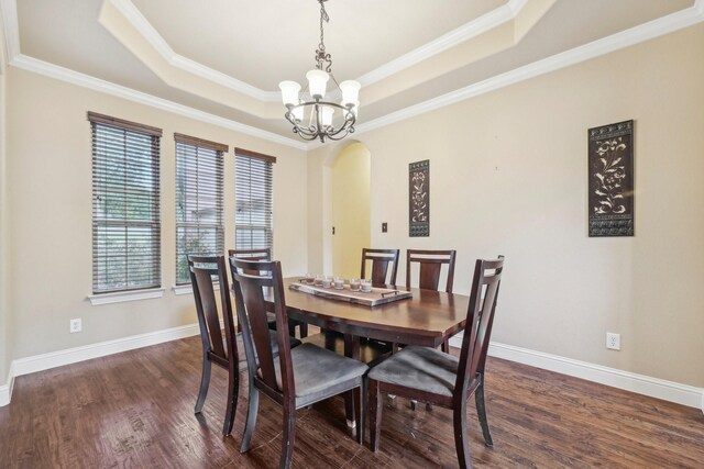 dining room featuring a notable chandelier, a tray ceiling, dark hardwood / wood-style floors, and crown molding