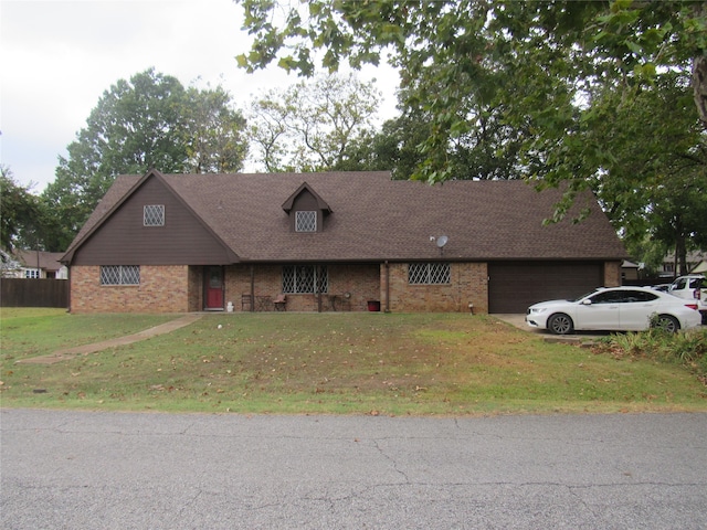 view of front facade featuring a front yard, a garage, brick siding, and driveway