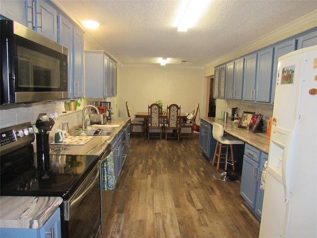 kitchen featuring a sink, stainless steel appliances, dark wood-type flooring, built in desk, and crown molding