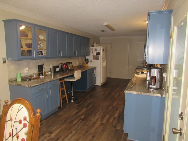 kitchen with blue cabinets, ornamental molding, dark wood finished floors, white fridge with ice dispenser, and glass insert cabinets