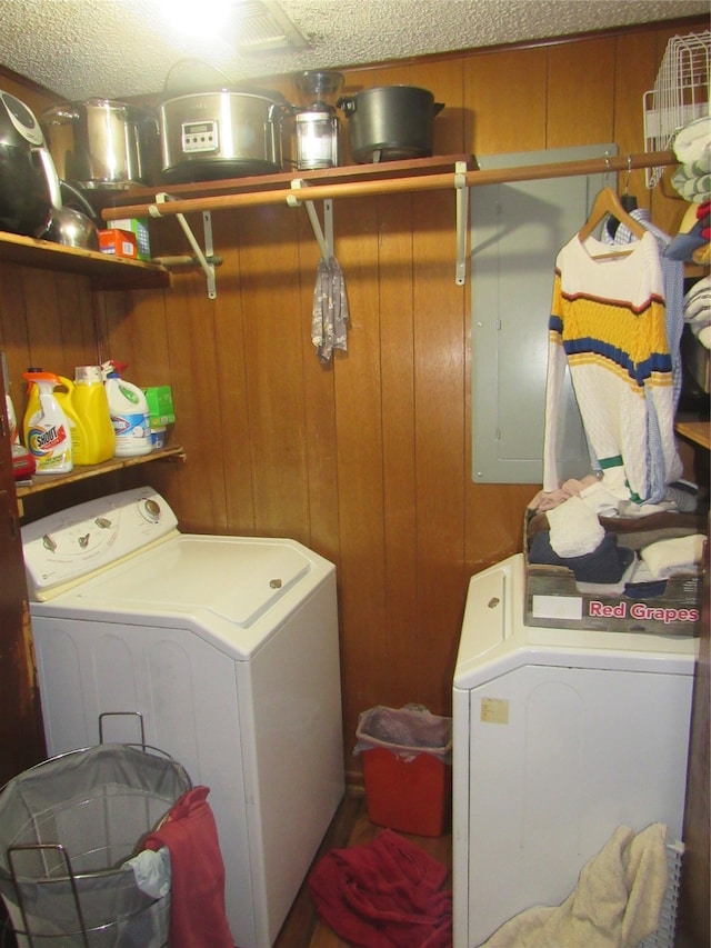 clothes washing area featuring wooden walls, a textured ceiling, laundry area, and washing machine and clothes dryer