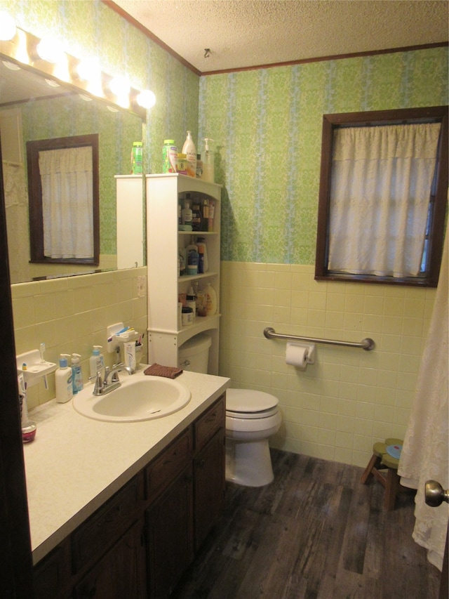 bathroom with tile walls, a textured ceiling, hardwood / wood-style flooring, vanity, and toilet