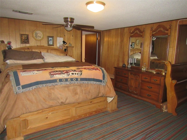 carpeted bedroom featuring visible vents, wooden walls, and a textured ceiling