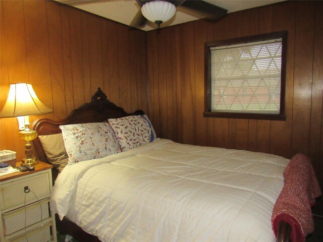 bedroom with a textured ceiling, wood walls, and ceiling fan