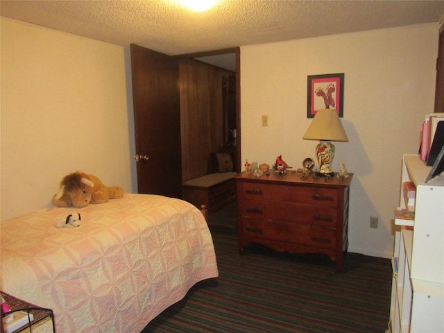 bedroom featuring dark carpet and a textured ceiling